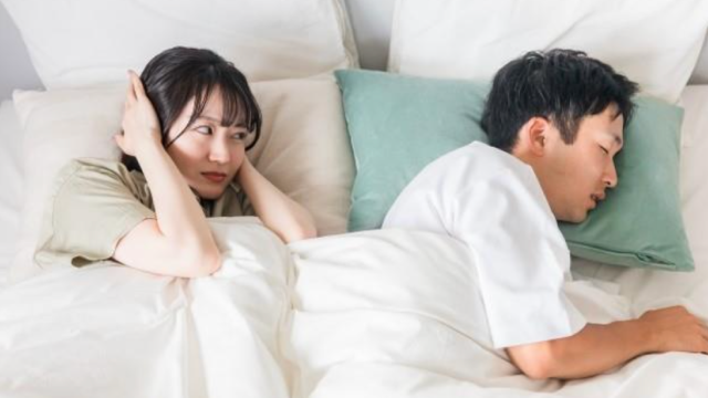 夫のいびきで耳を塞いでいる女性