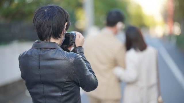 探偵が浮気現場を写真に撮っている様子