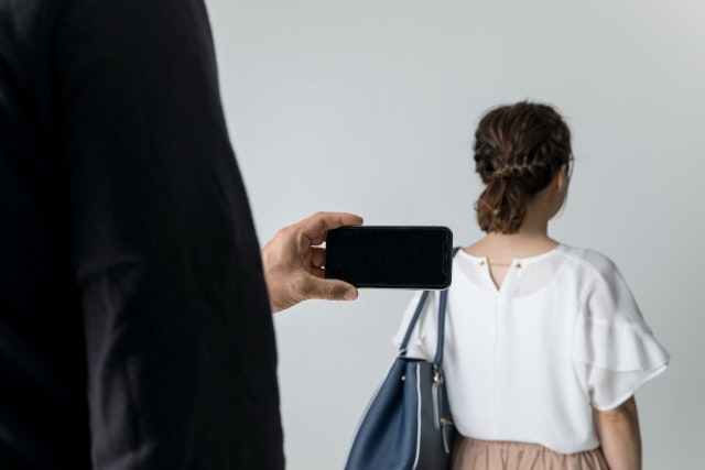 女性の後ろ姿を撮影している男性