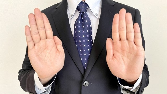 手を押し返すスーツを着た男性