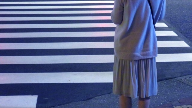 夜の横断歩道で信号待ちをする女性