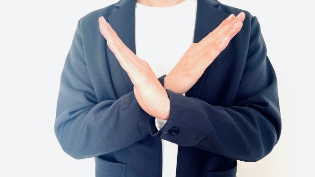 手でバツ印をする男性