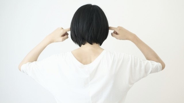 耳を塞ぐ女性