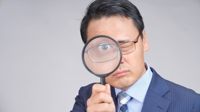 虫眼鏡を覗く興信所のスタッフ