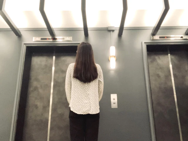 別の階のオフィスにエレベータで移動する女性