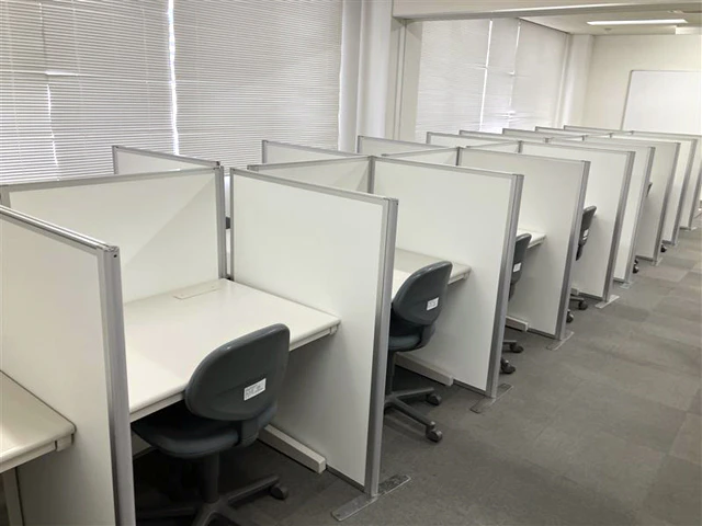 隣接する机をパーテーションで仕切ったオフィス