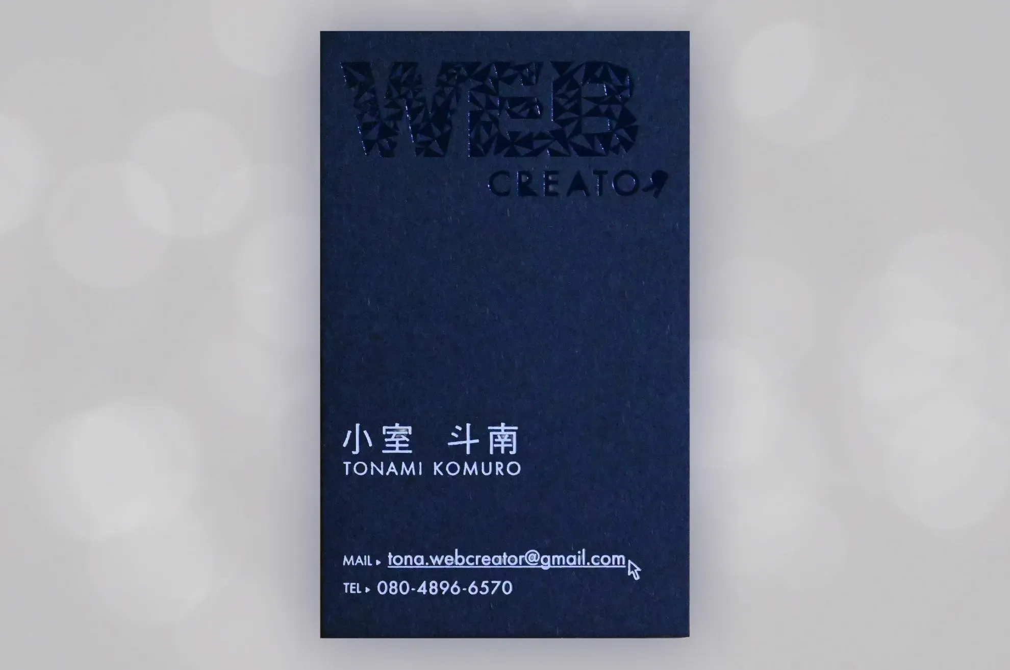 Business card front - White text on navy paper showing name and contact information