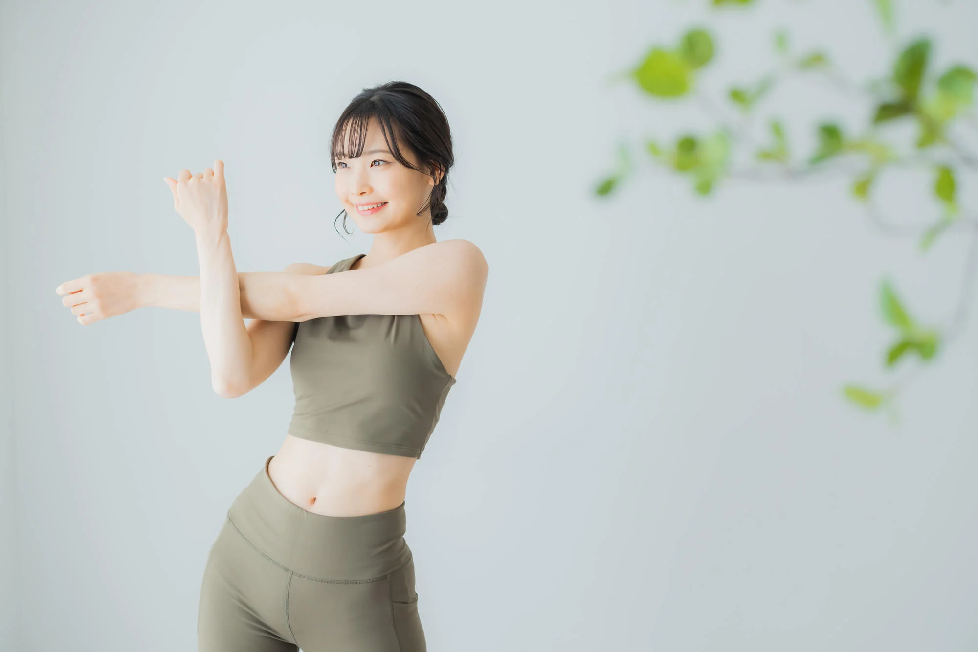 ピラティスウェアを着用して、笑顔で準備運動をする女性