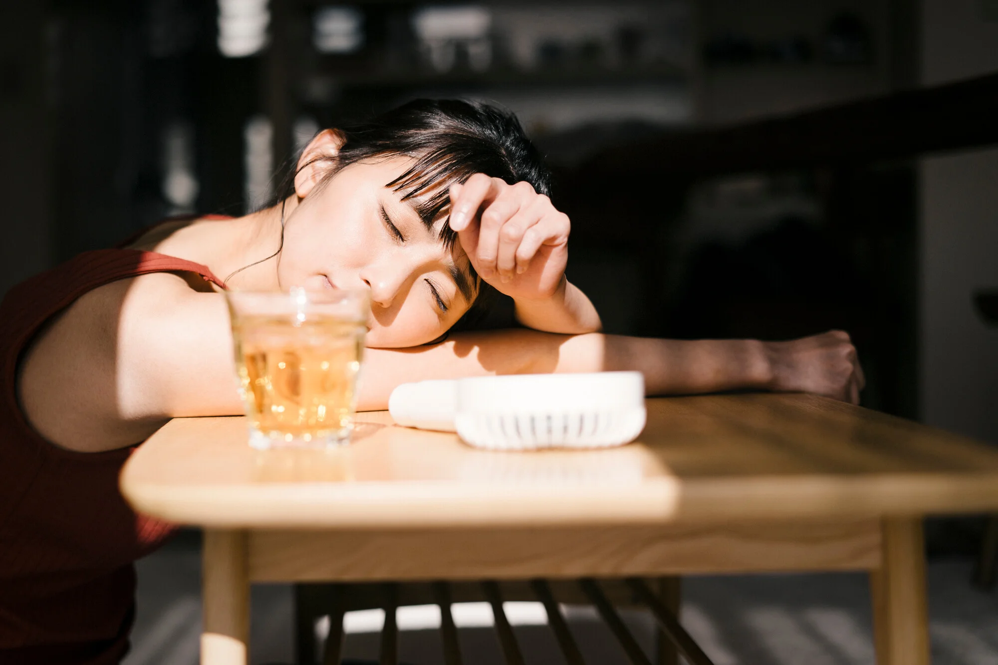 日差しの当たる室内でぐったりとテーブルに伏せる女性