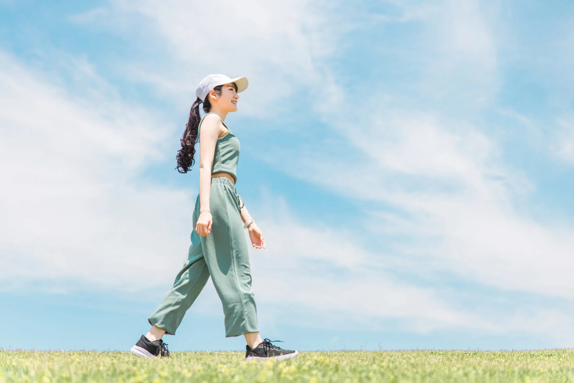 晴天の日に帽子をかぶりウォーキングをする女性