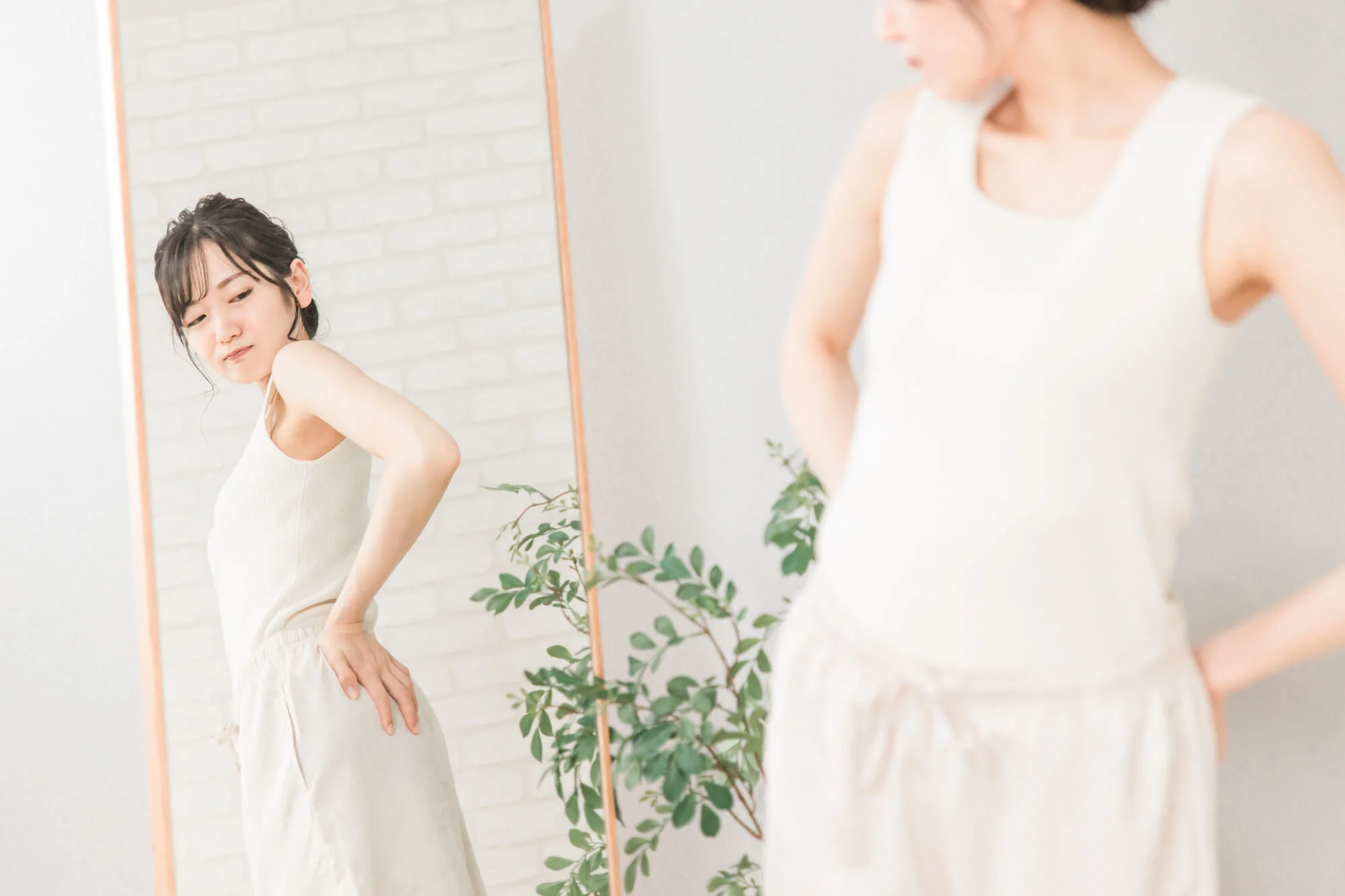 鏡を見ながら腰の辺りを気にする女性