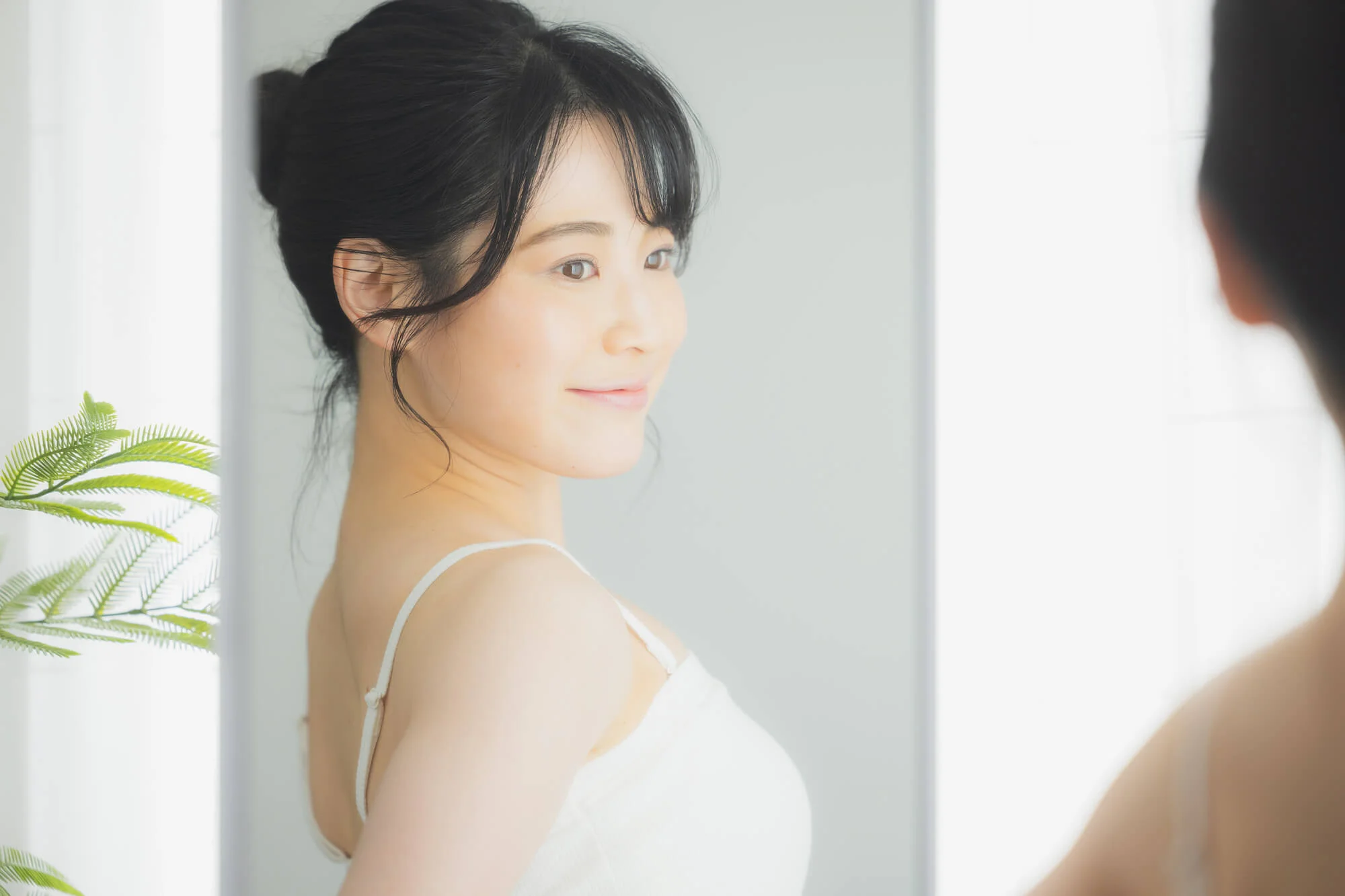 鏡の前で背筋を伸ばす女性