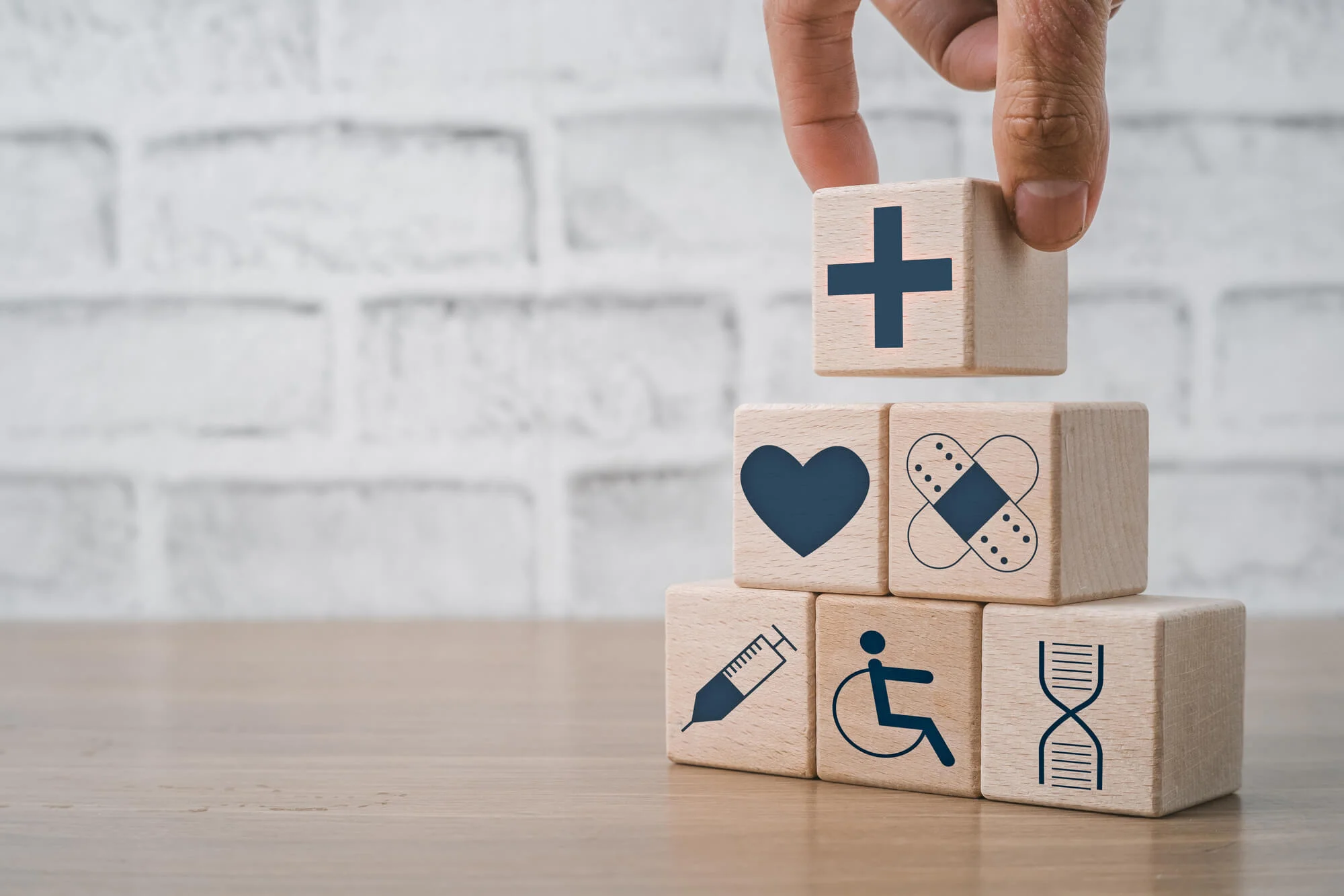 健康・医療に関するイラストが描かれた積み木と、それを積み上げる人の手