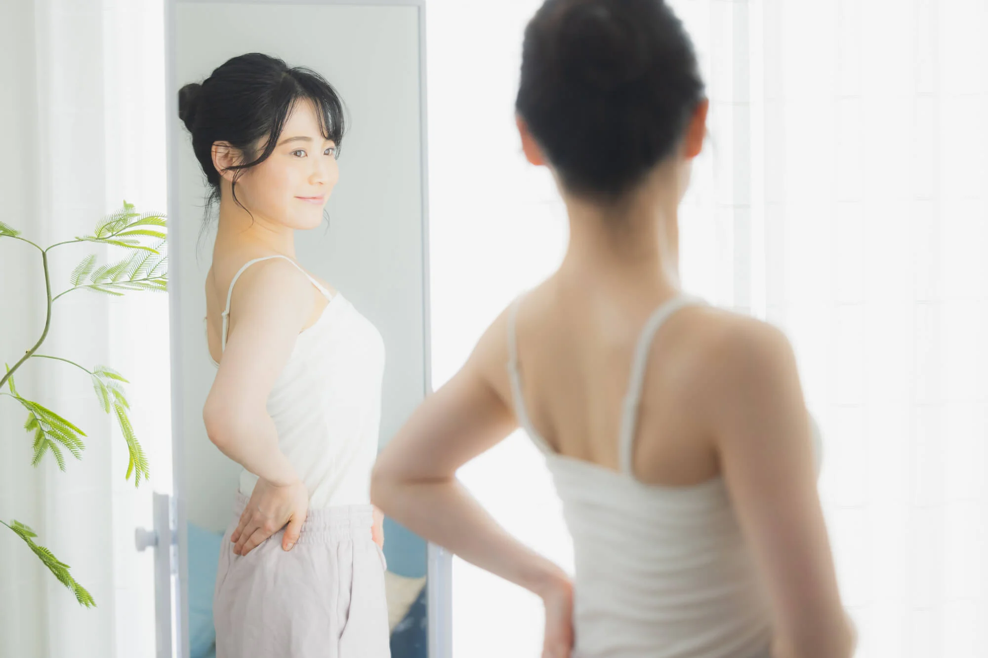 鏡に映った自分の姿を見てほほ笑む女性