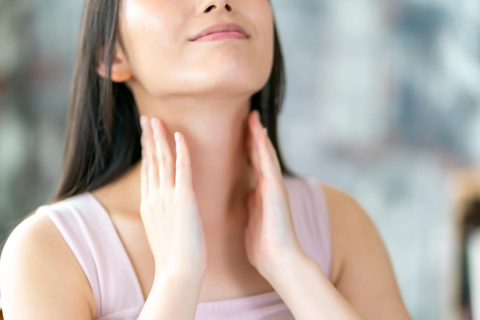 上を向いて首を触る女性