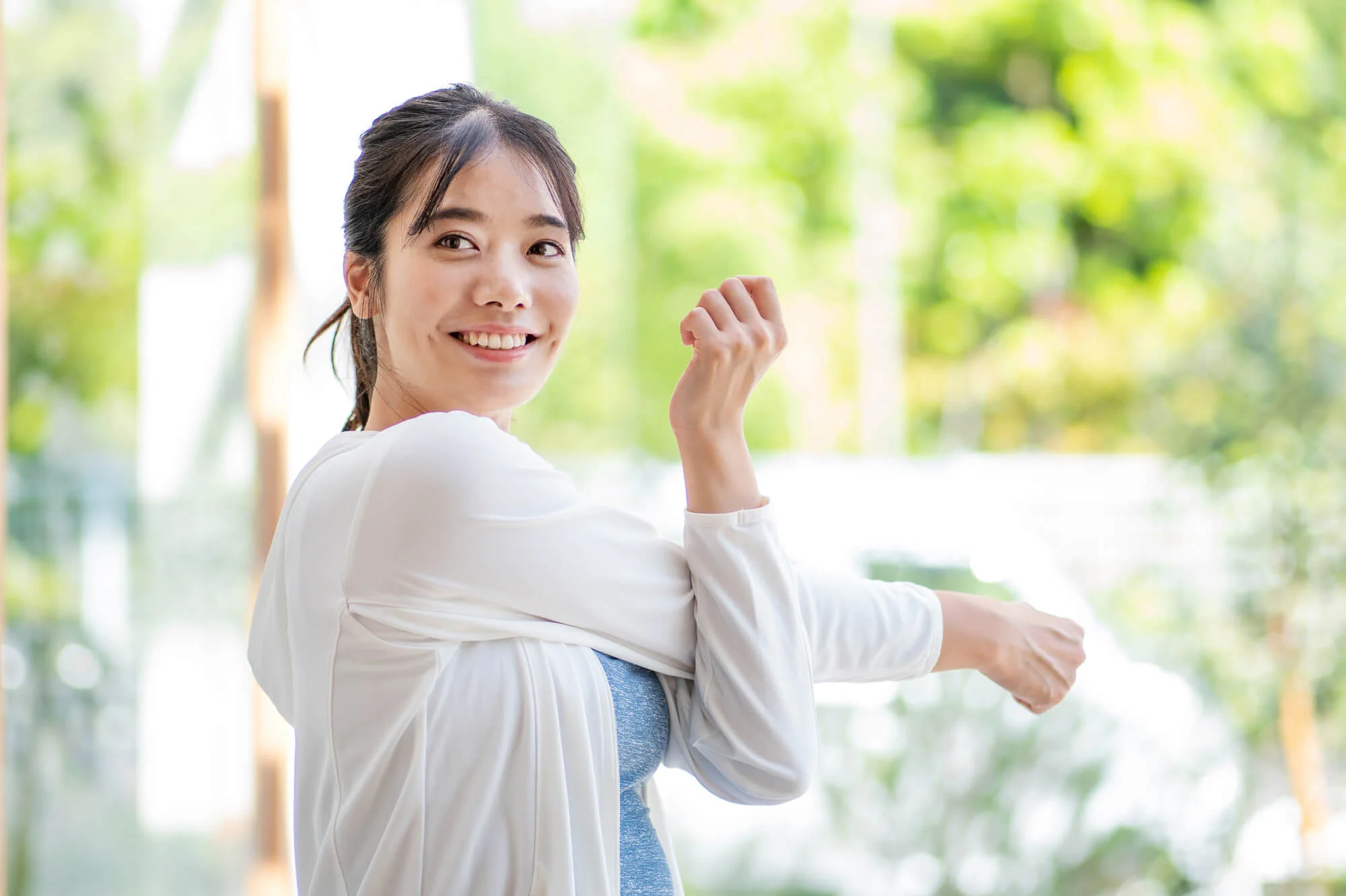 運動前の準備体操をしながらほほ笑む女性