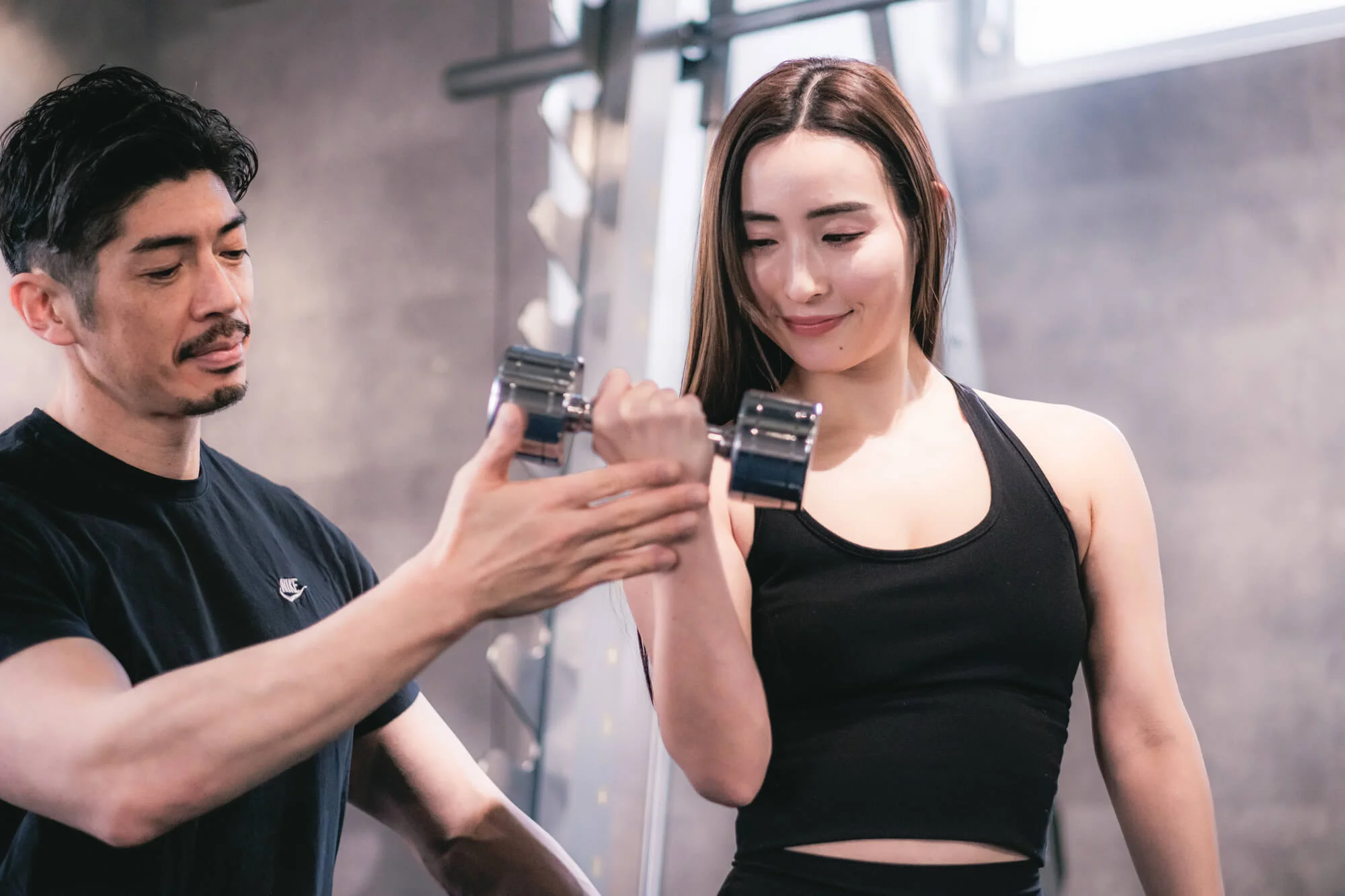 指導を受けながらダンベルを持ち上げる女性