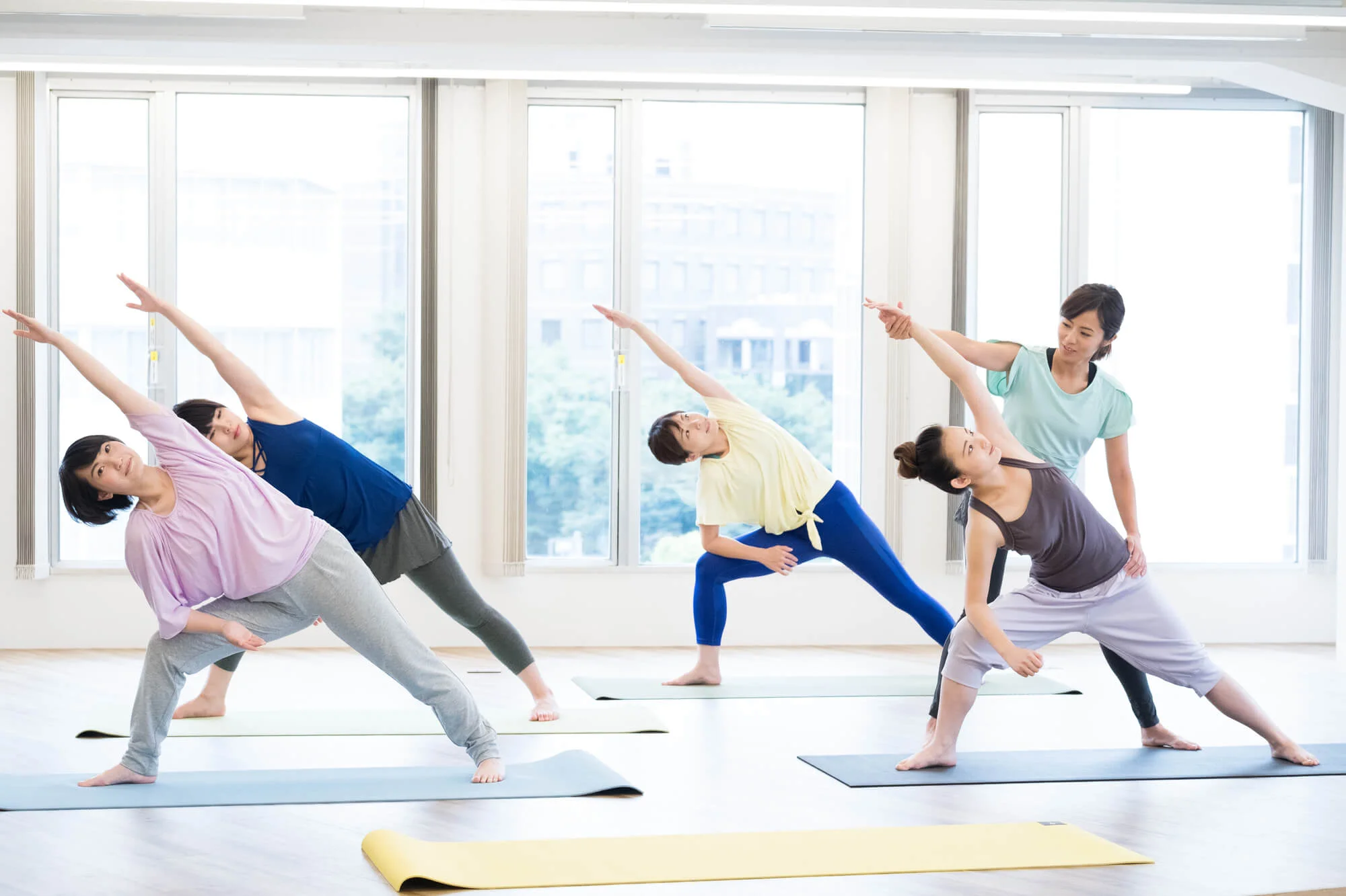 ヨガのポーズを教えるエデュケーターとレッスンを受ける女性たち