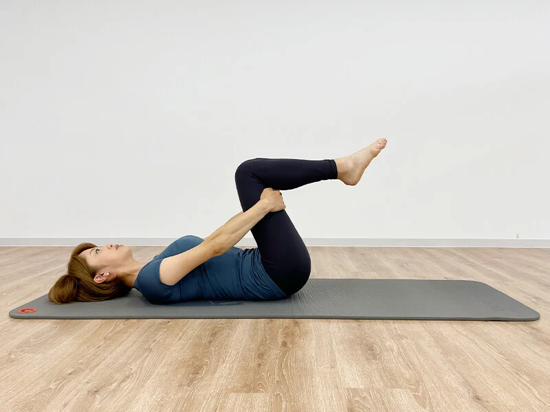 ももの裏を抱えて仰向けになる女性