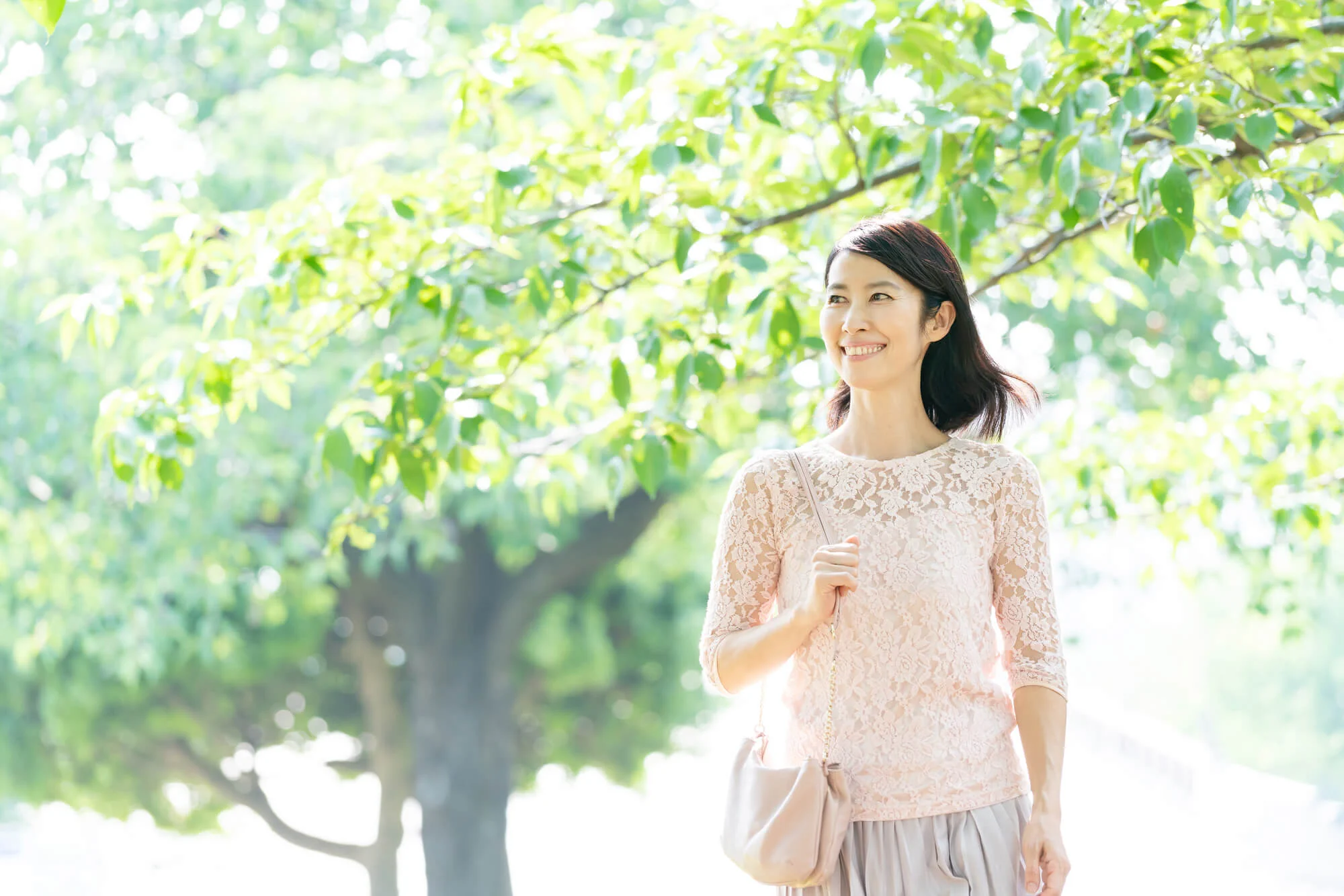 森林の中を散歩しながら、生き生きとした笑顔の女性