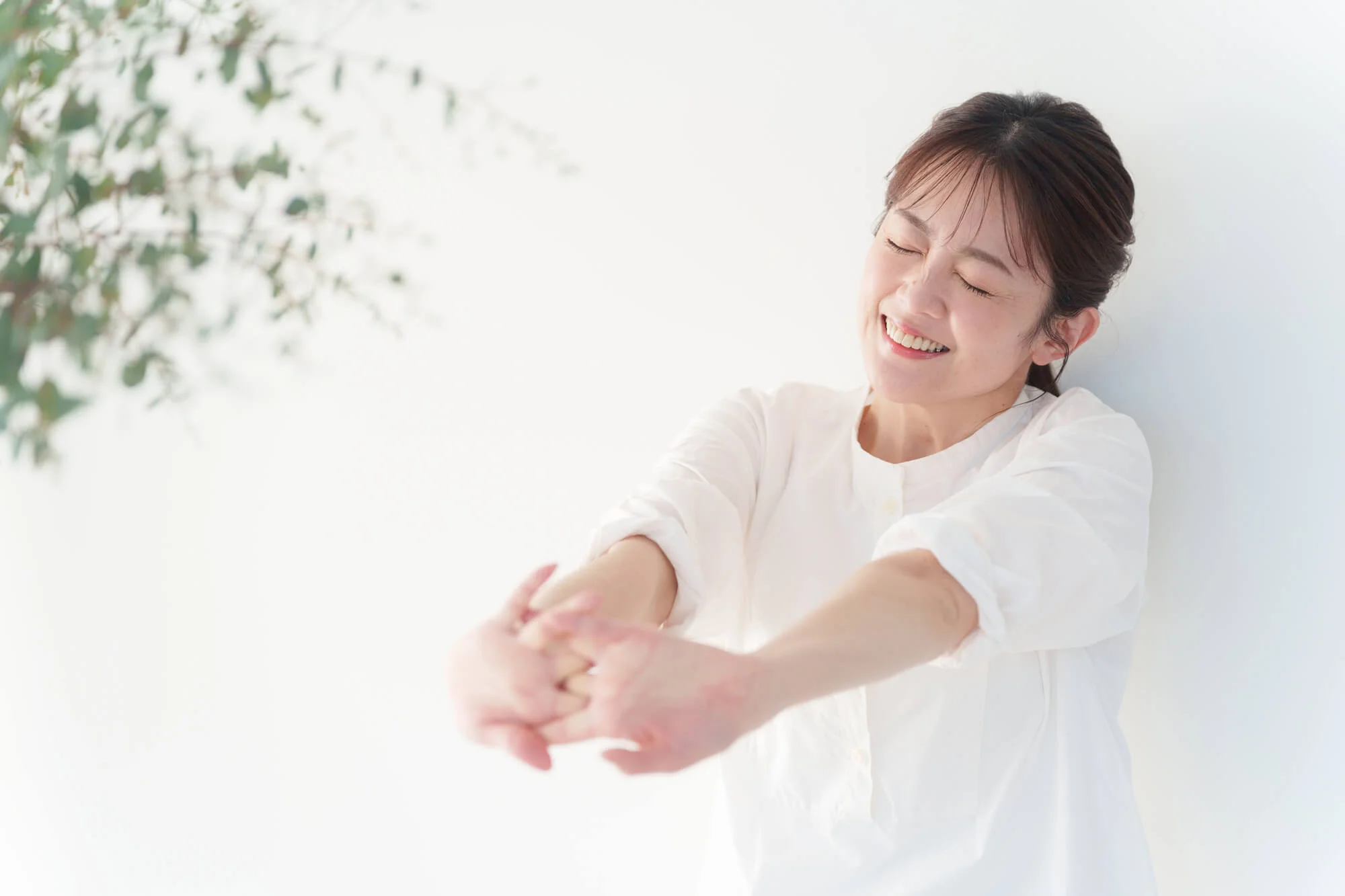組んだ手を前に伸ばしてストレッチする女性