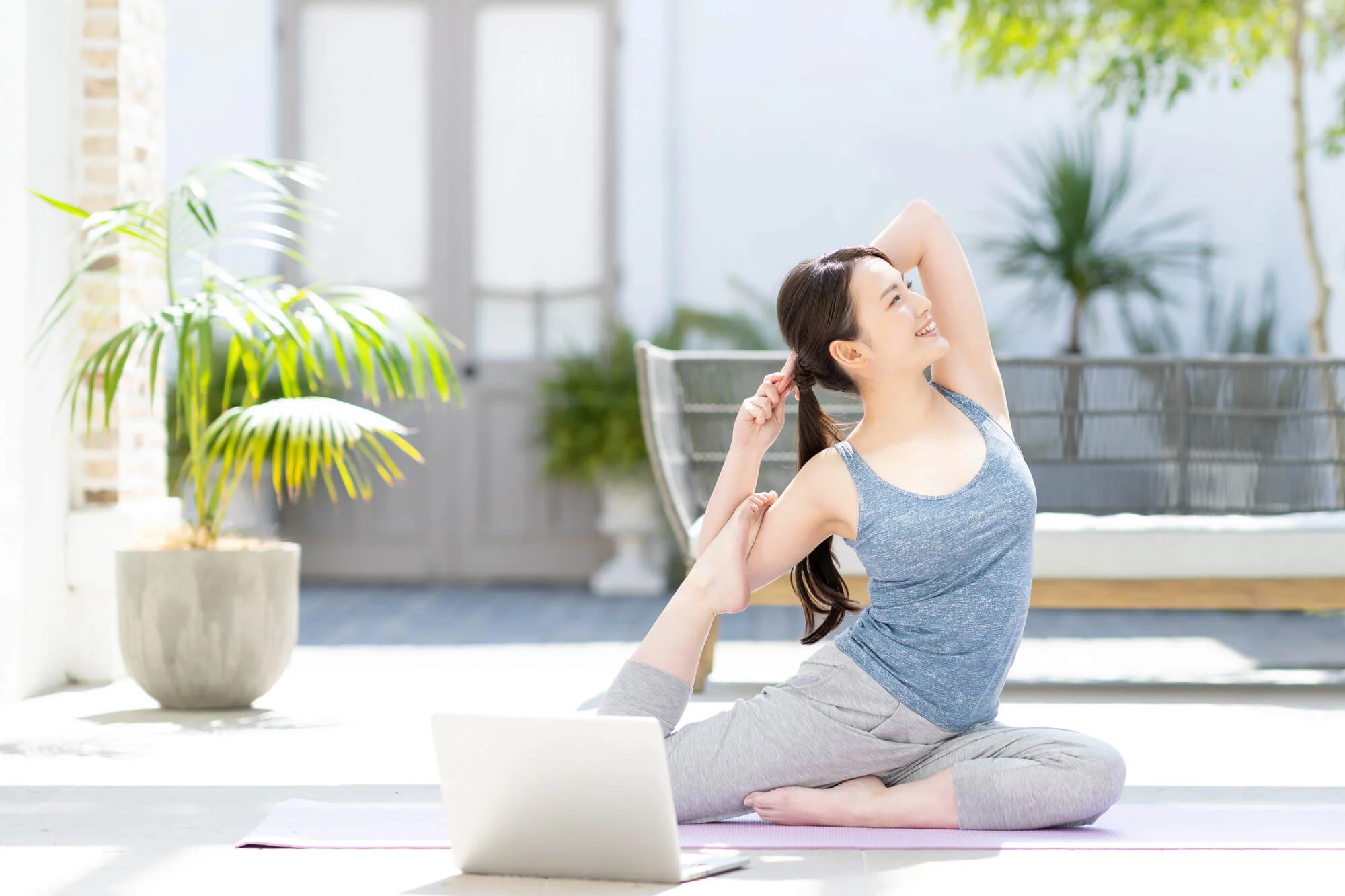 パソコンの前でヨガを行う女性