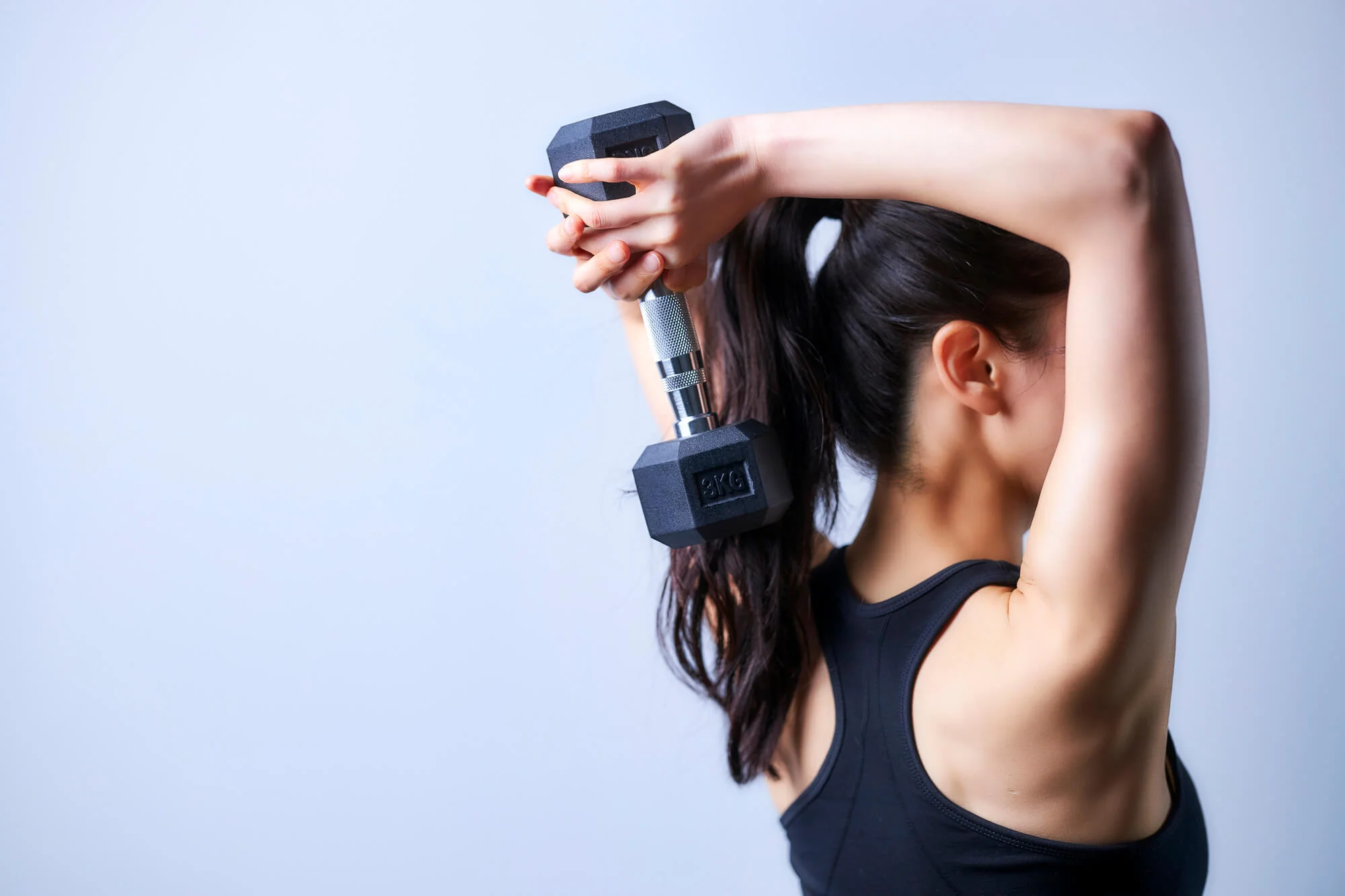 ダンベルを背面で持ち上げる女性