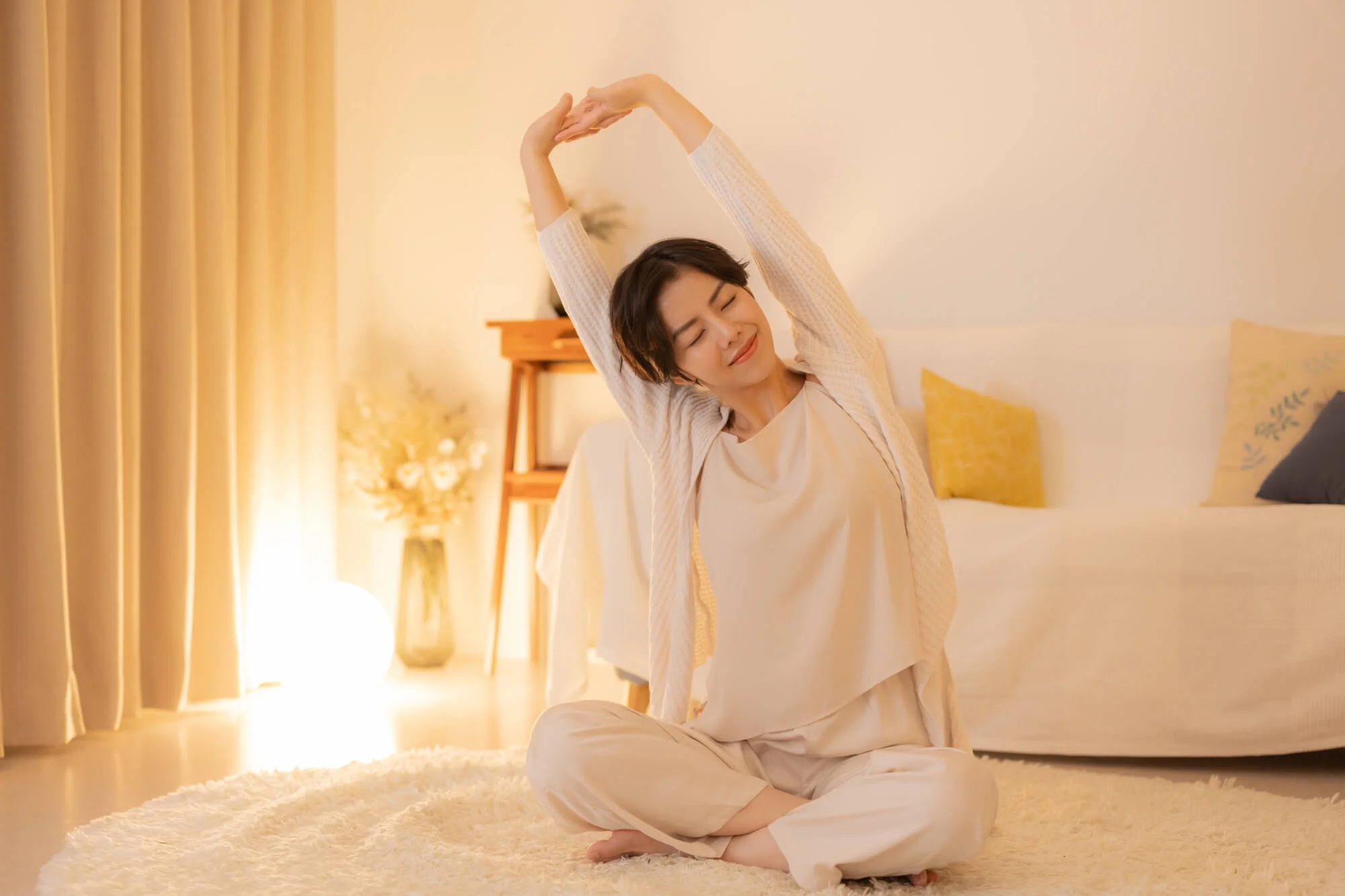 あぐらを組み、伸びをする女性