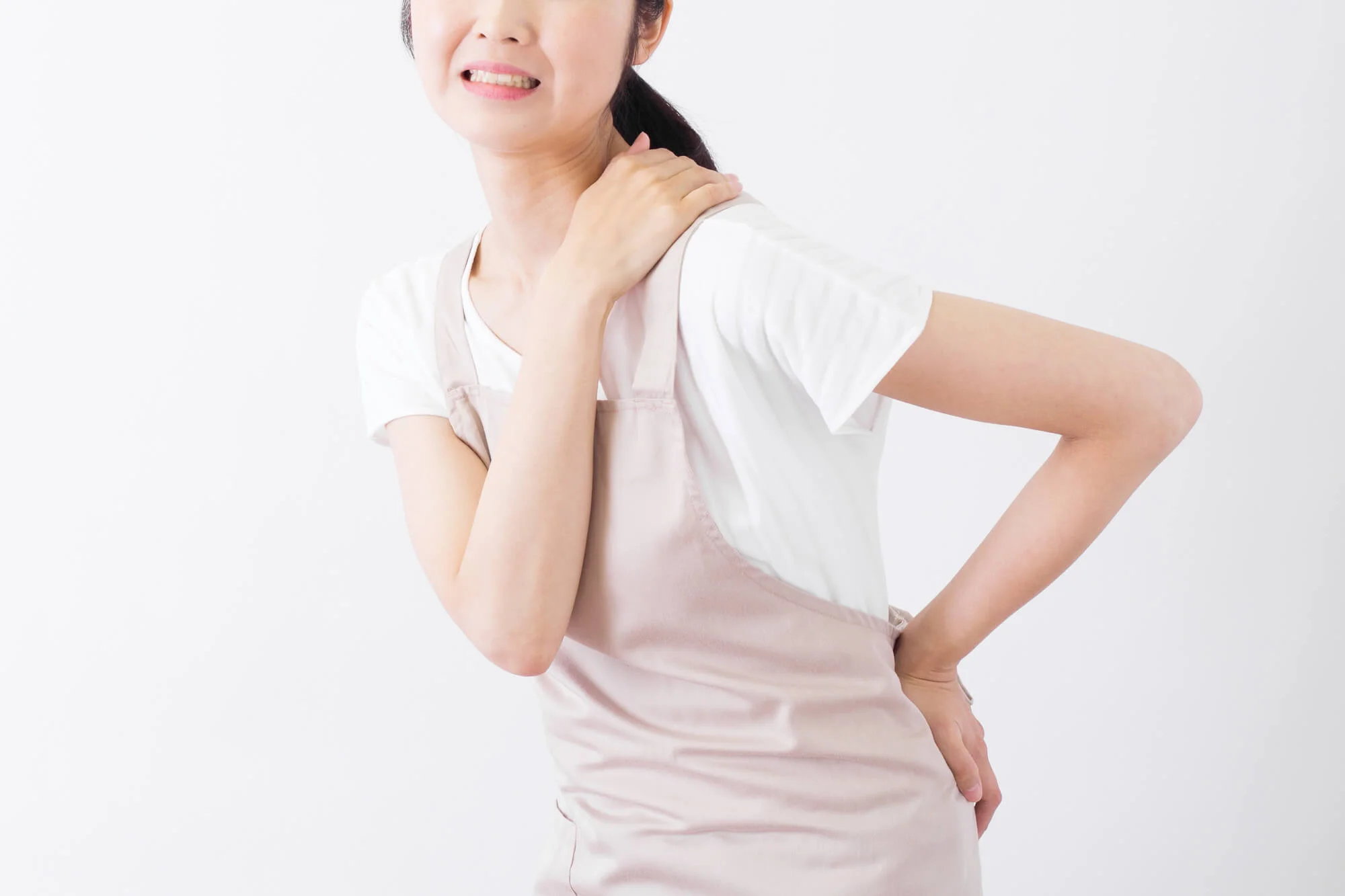 腰と肩を抑えながら痛そうな表情を浮かべる女性