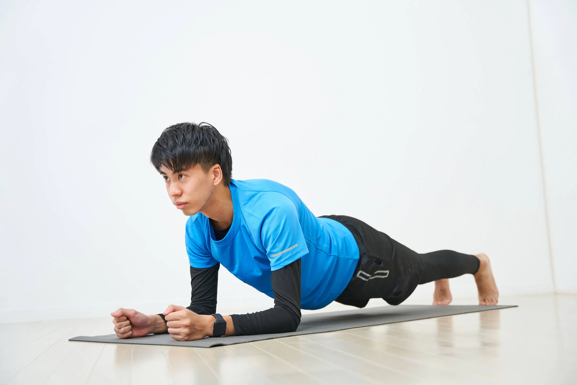 室内でピラティスのプランクをする男性