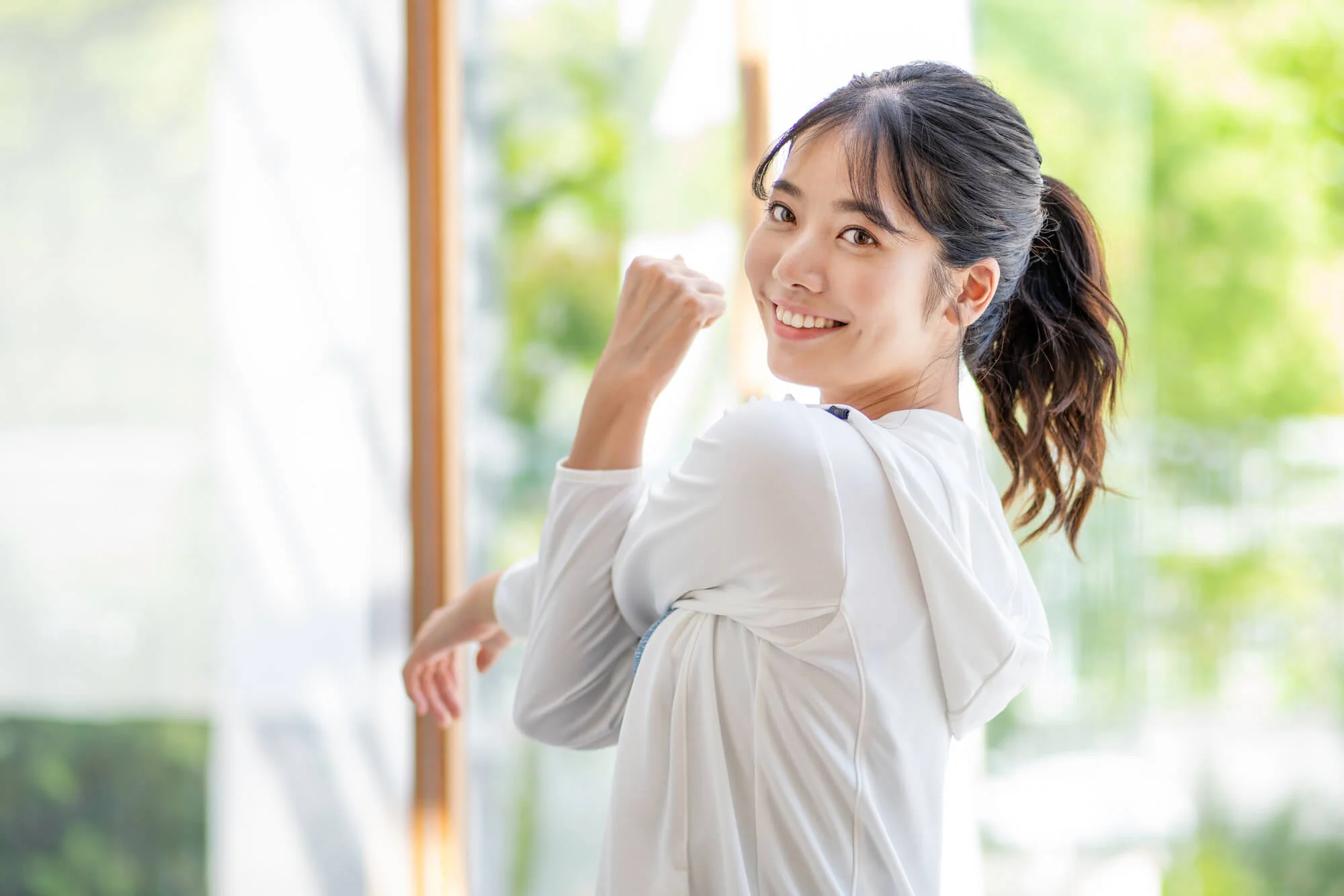 笑顔でストレッチをするポニーテールの女性