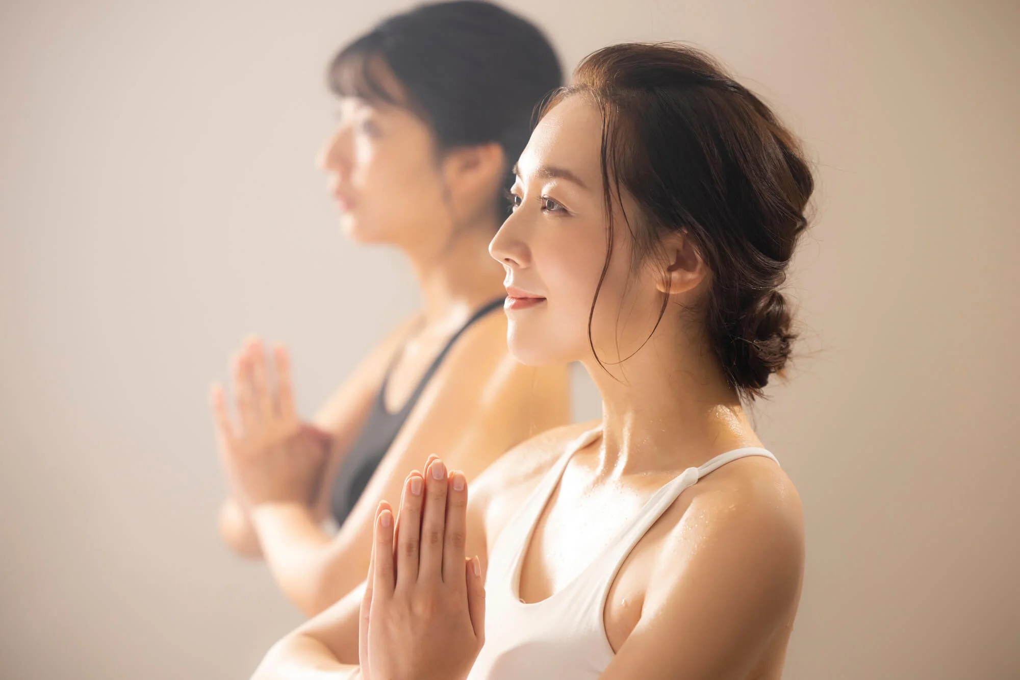 胸の前で手を合わせる2人の女性