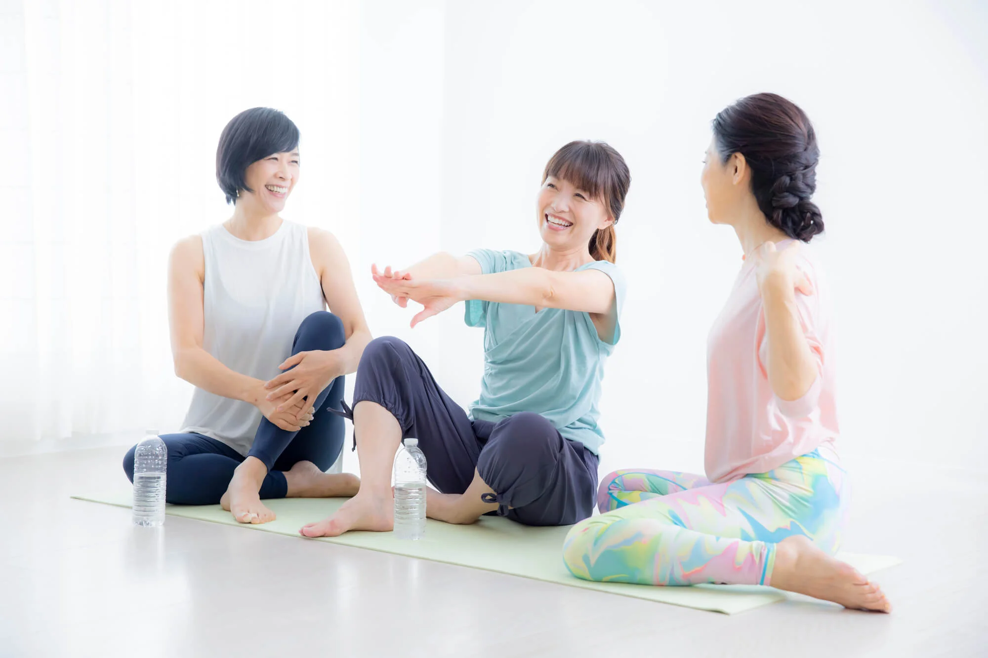 ヨガマットの上で談笑する3人の女性