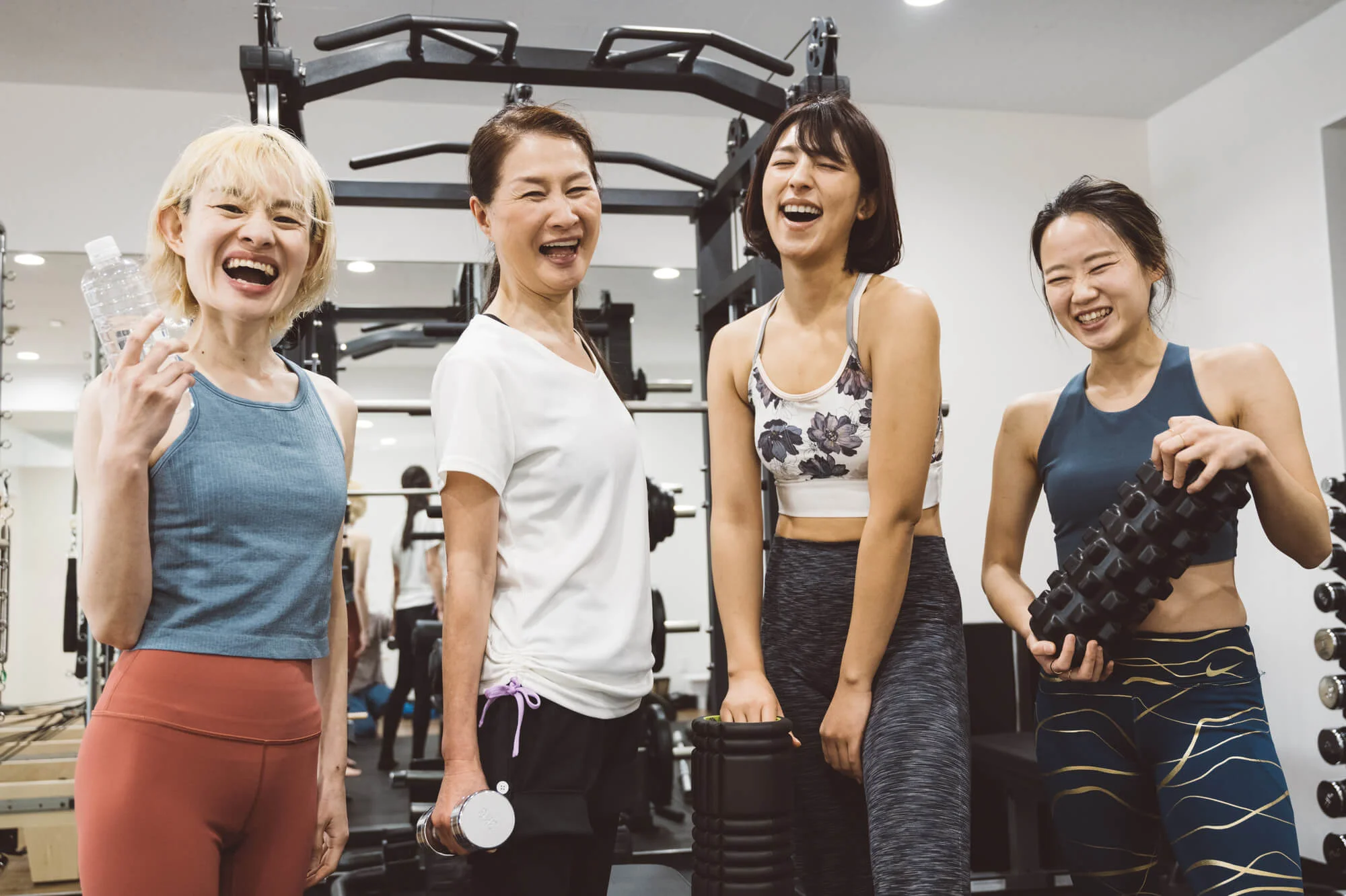 筋トレマシンの前で笑顔の女性4人