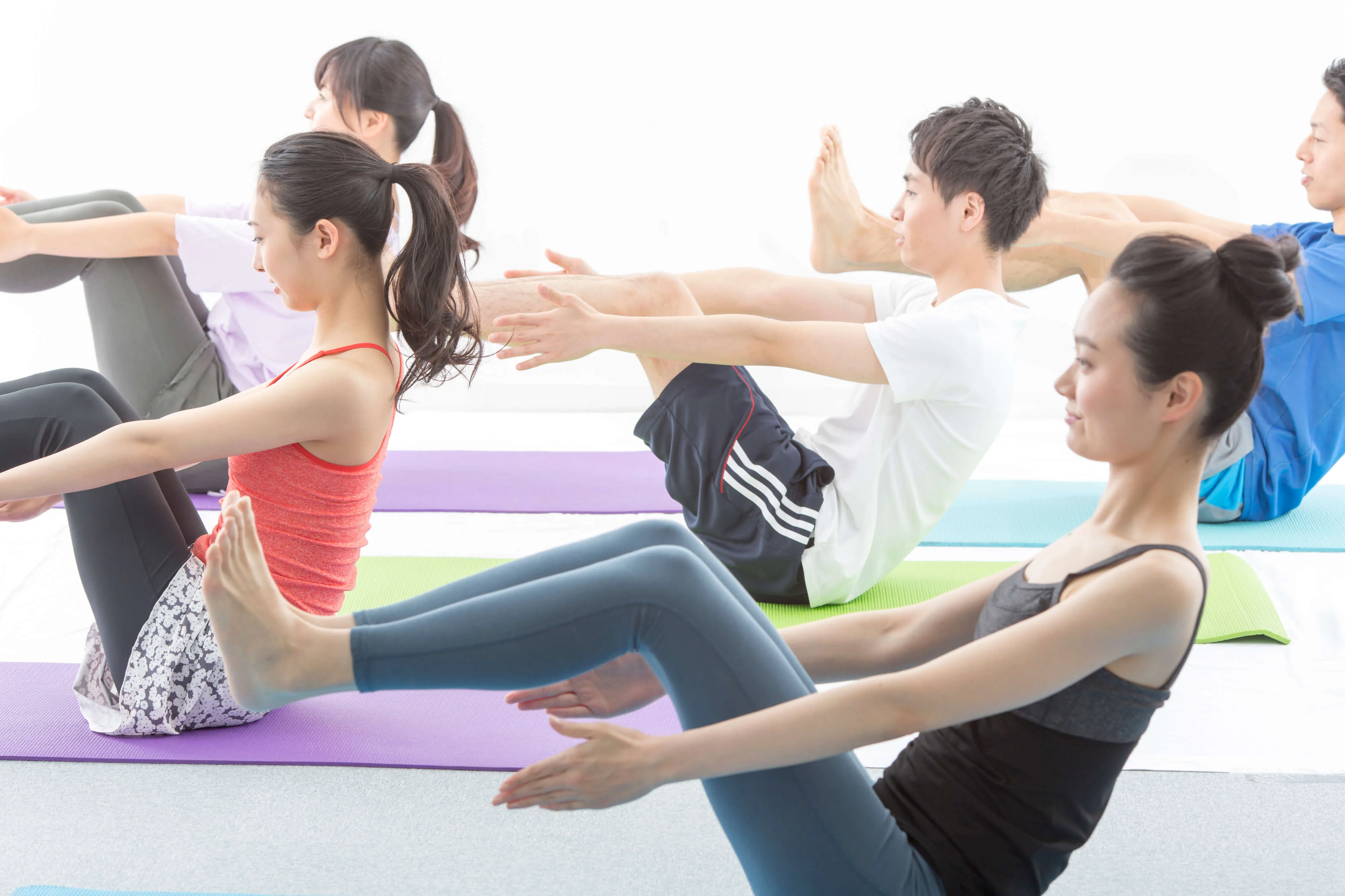スタジオで足と手を上げて腹筋を強化するピラティスを行う女性たち