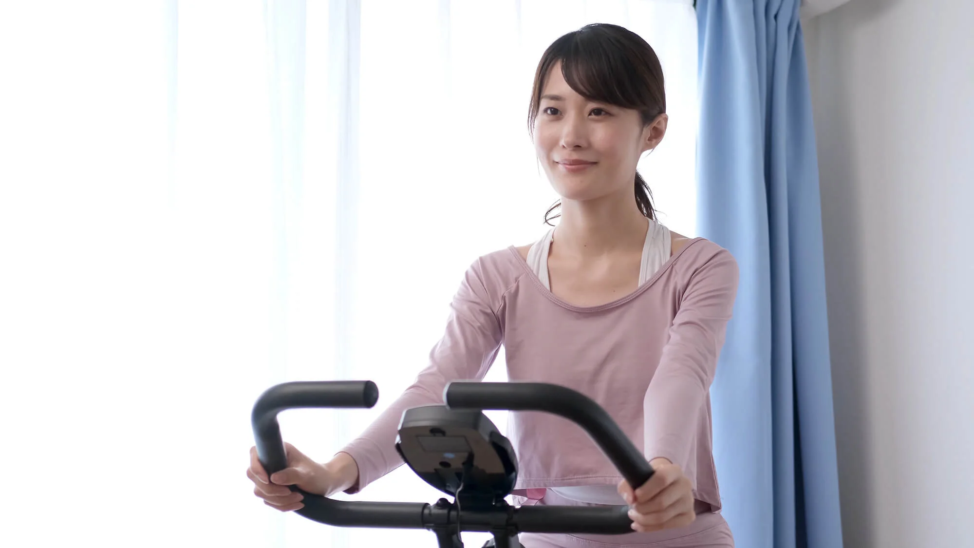 室内でエアロバイクをこぐ女性