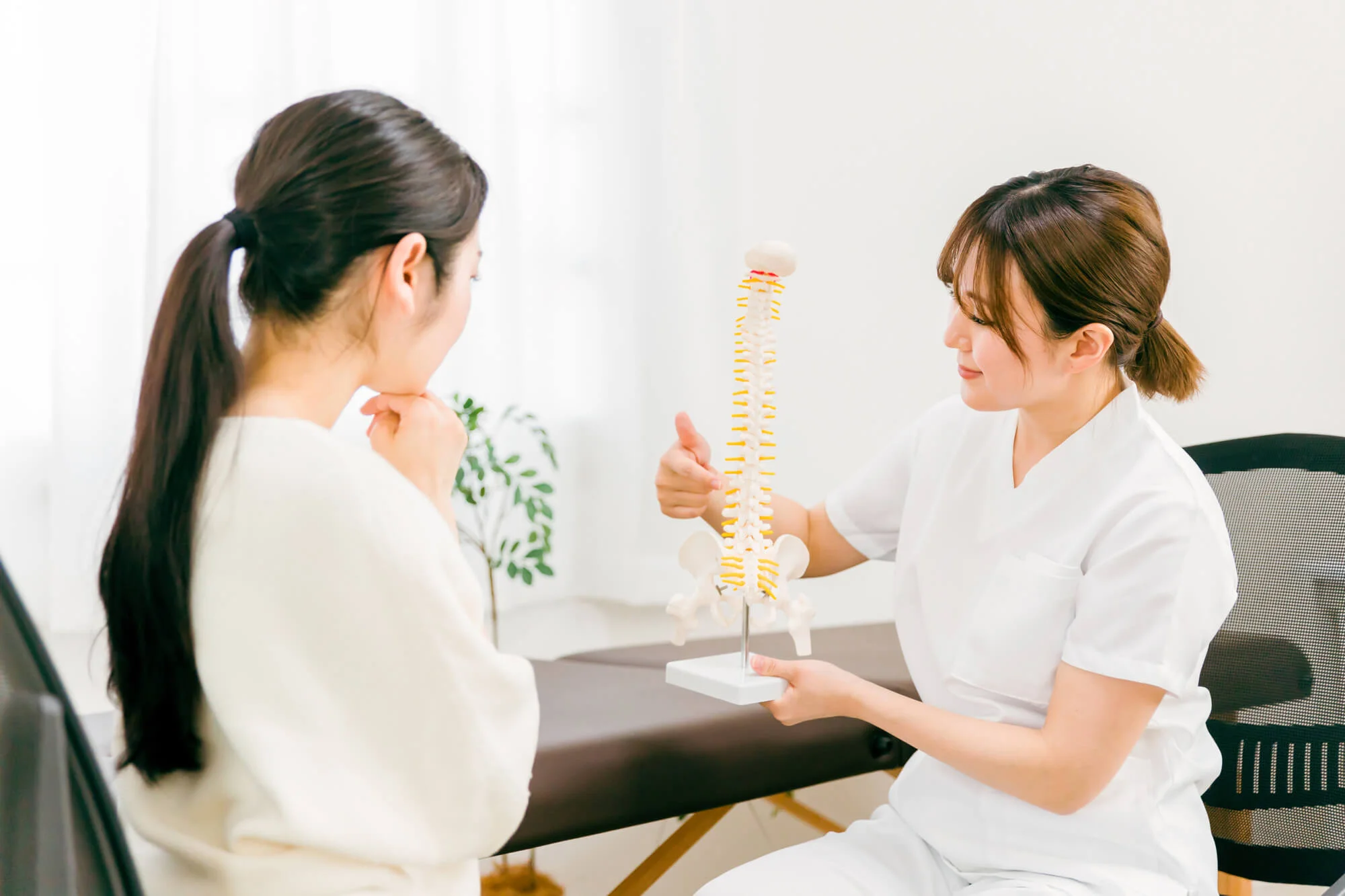 骨盤の模型を持ち説明をする女性と考え込む女性