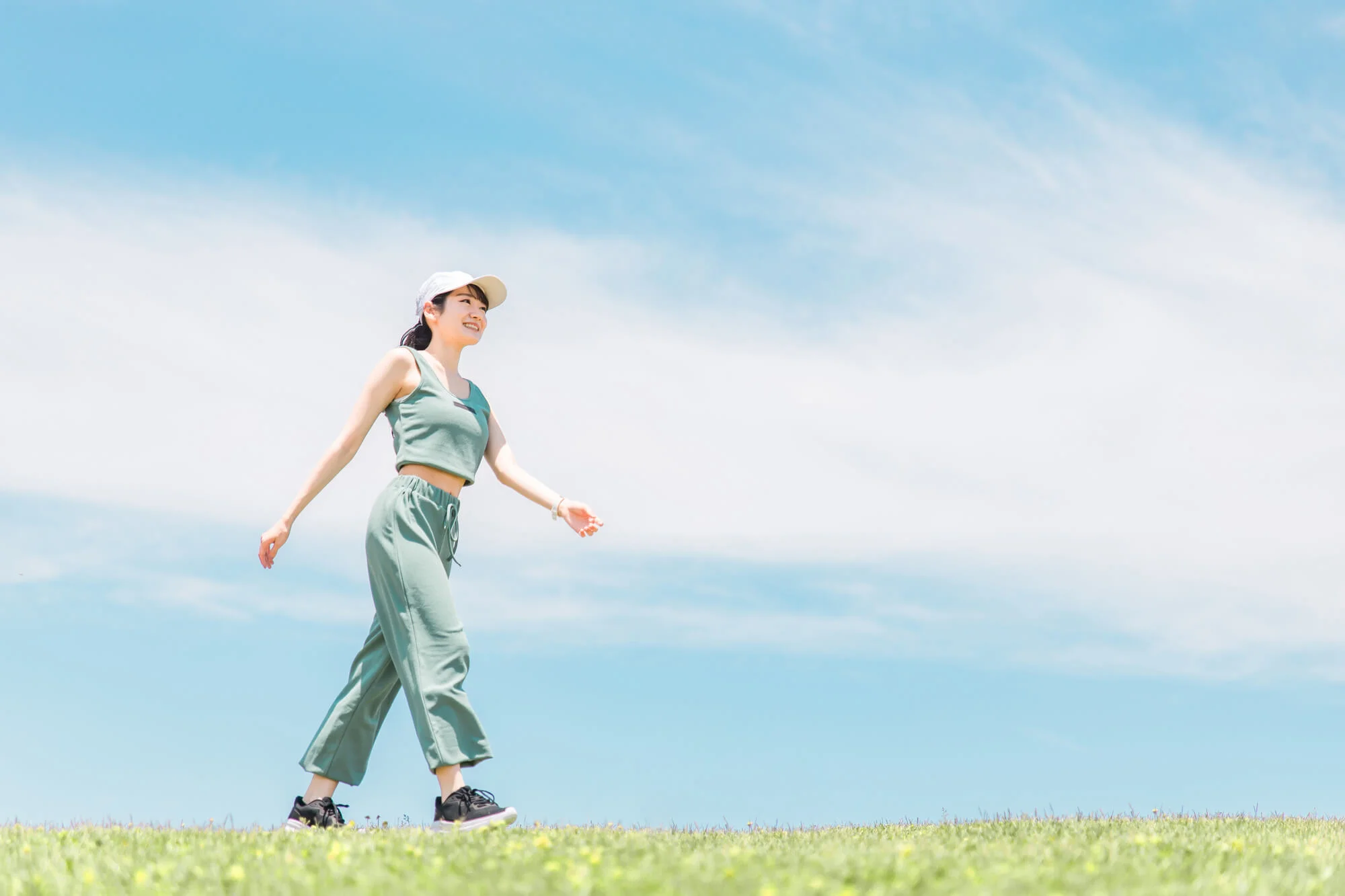 晴れた日に芝生の上を笑顔でウォーキングする女性