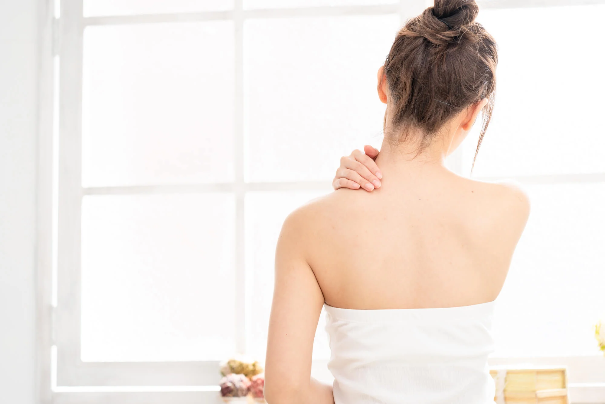 肩に手を当てる女性の後ろ姿