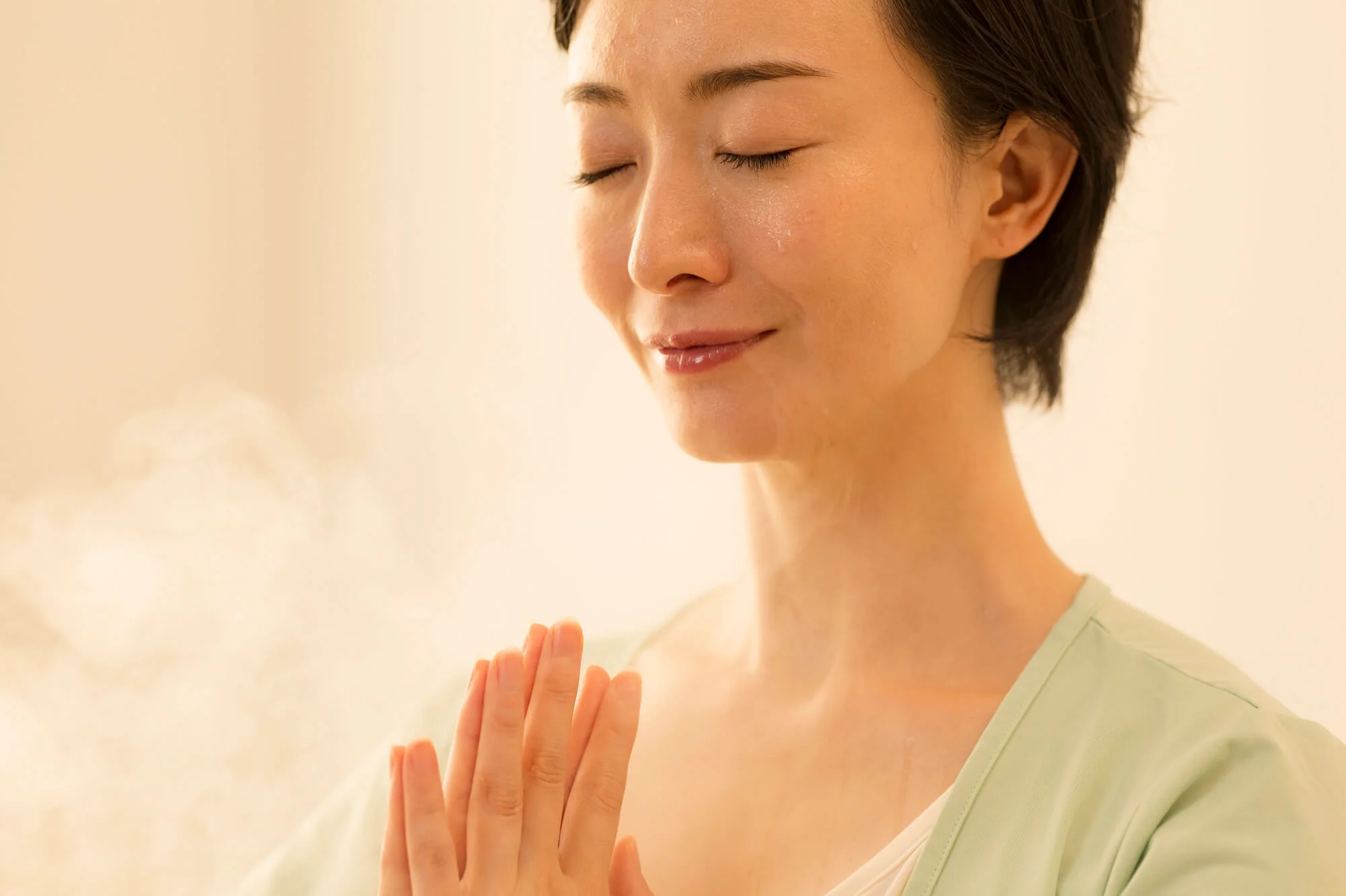 目を閉じて胸の前で手を合わる女性