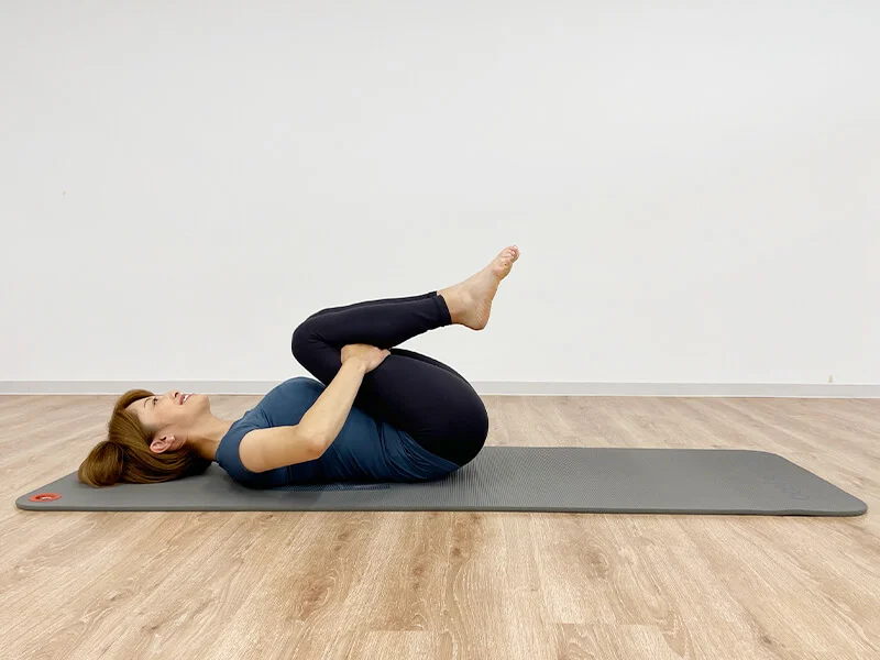 膝の裏を抱えて仰向けになる女性