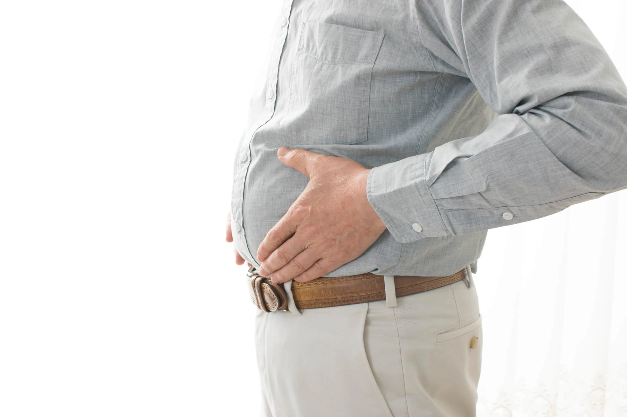 ぽっこりとしたおなかをおさえる男性