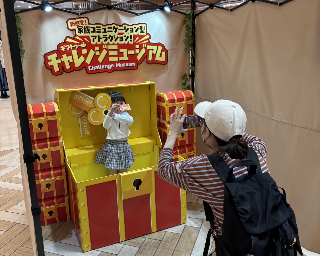 大きな宝箱に入った子どもを家族が撮影するチャレンジミュージアムの実施写真