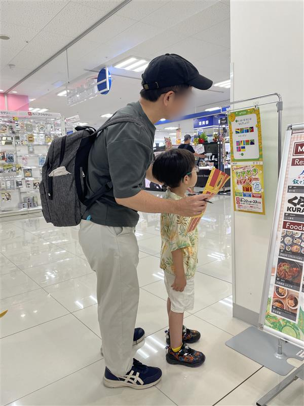 館内のなぞ掲示と手元の台紙を親子で一緒に見る様子