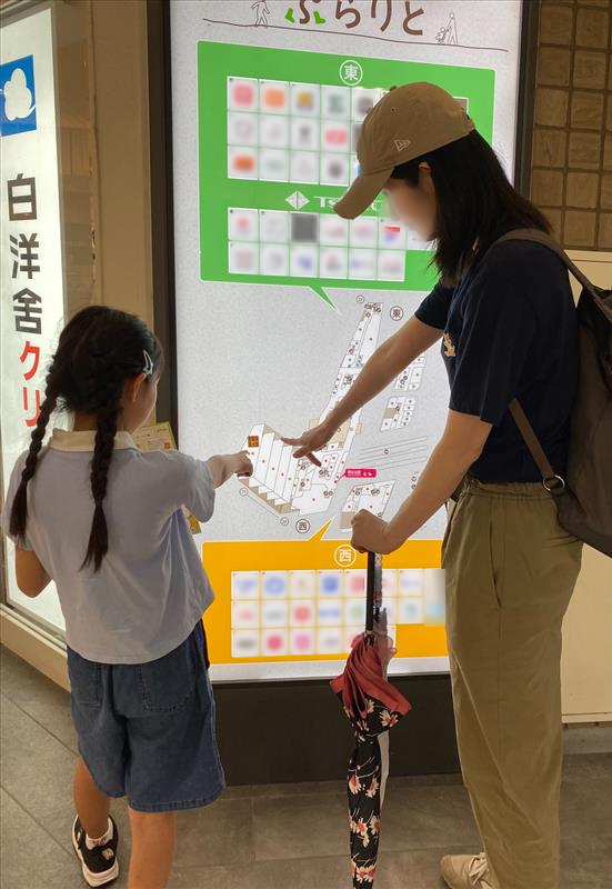 子どもと同行者がぷらりと京王府中の館内案内図を指し示して確認する様子