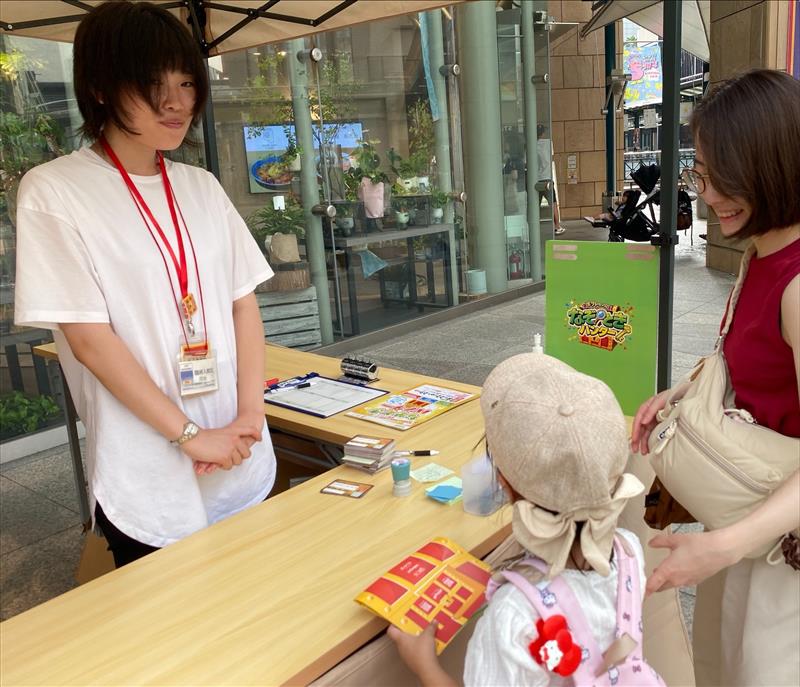 台紙を持った子どもと同行者が受付のスタッフと向き合う様子
