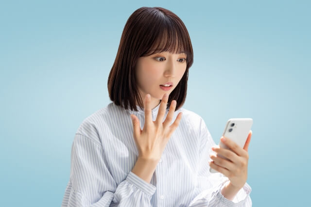 スマートフォンを見て驚く女性