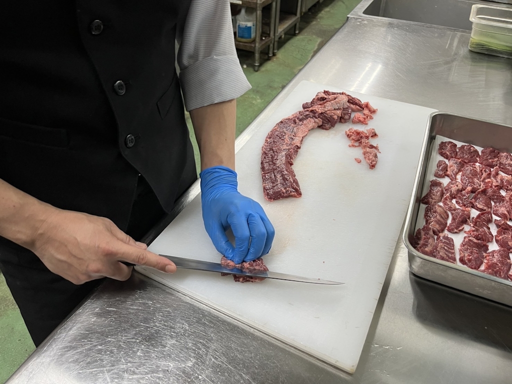 肉のカットは「切って→測る」を繰り返し練習。1ヶ月ほどで指定のグラム感覚が自然と身につきます。包丁に触れたことがあれば十分スタート可能です。