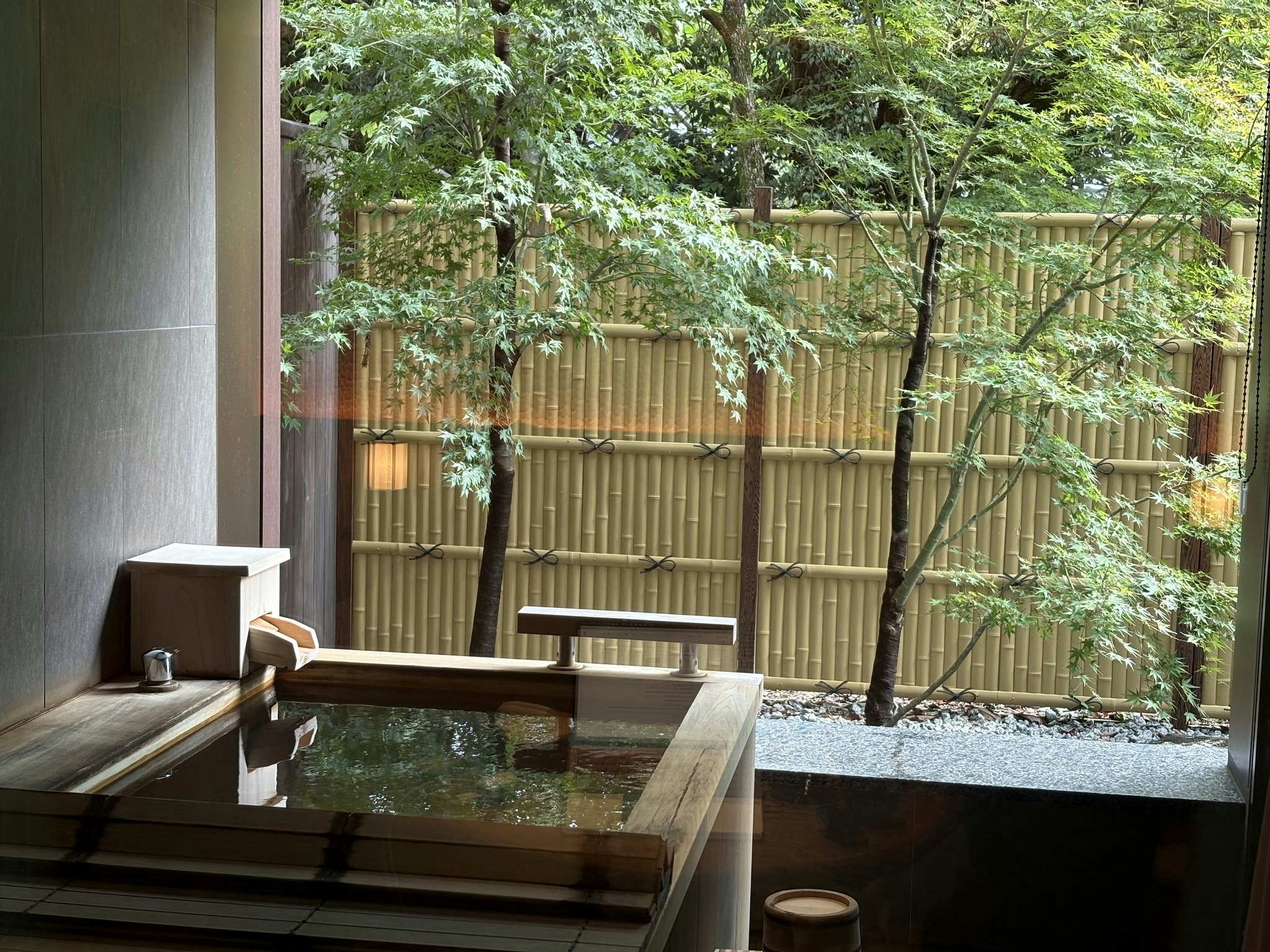 紫翠の客室露天風呂。緑に囲まれた檜風呂と竹垣