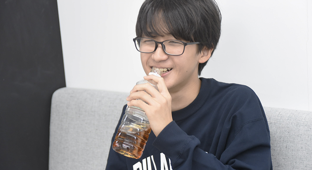 インタビューの合間に、ペットボトルのお茶を飲んで一息つく一宇くん。楽しそうに目を細めており、対談が和やかな雰囲気の中で行われていることがわかる一枚。